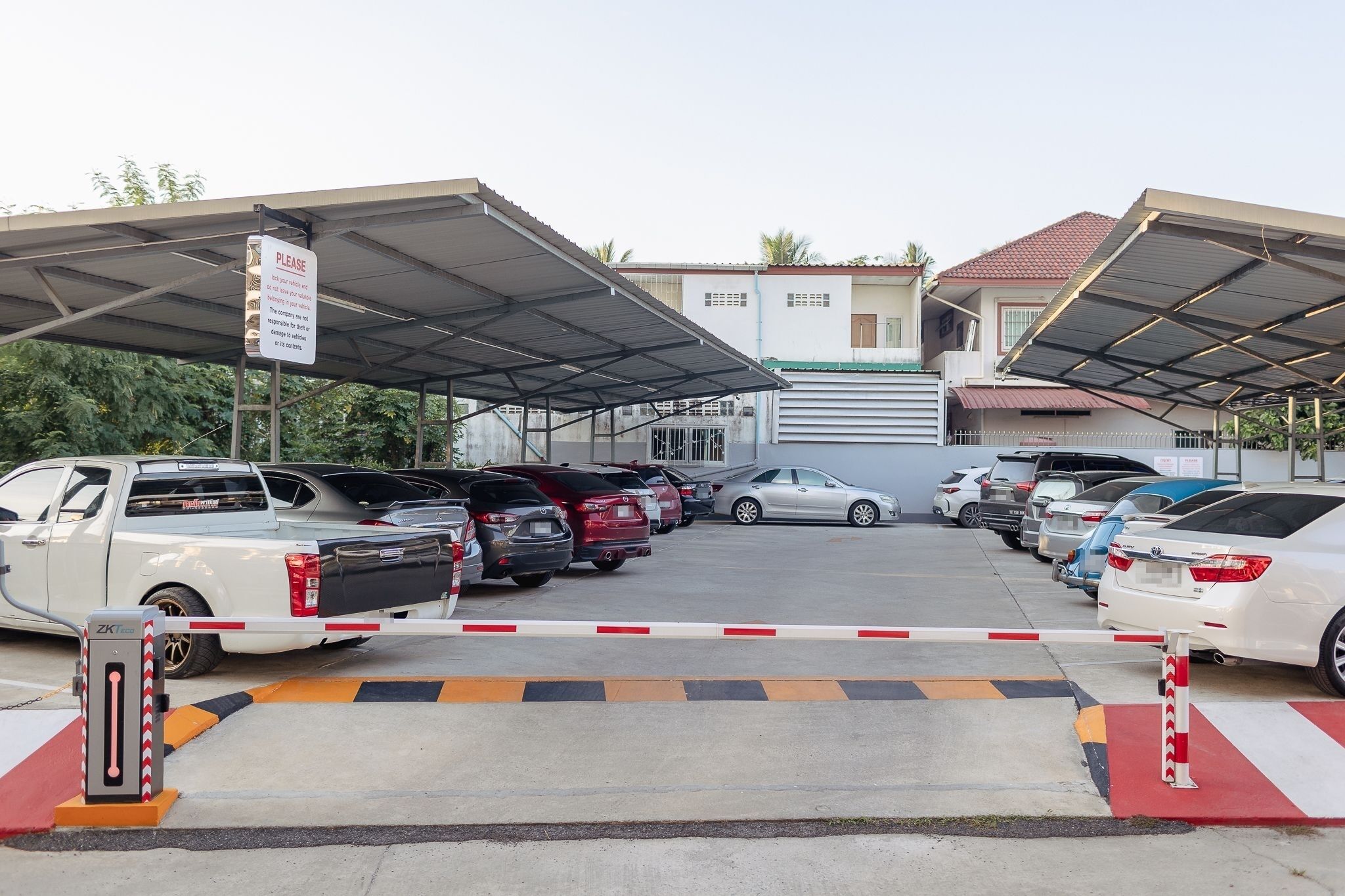 A parking area with multiple cars and a covered waiting area.