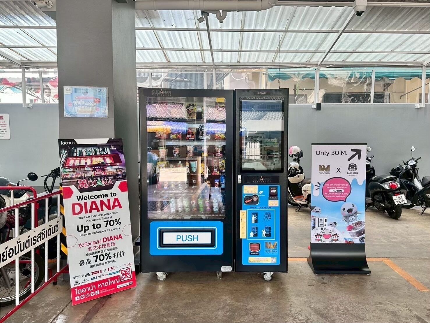 Un distributeur automatique doté d’un bouton-poussoir, entouré de panneaux publicitaires et d’un scooter.