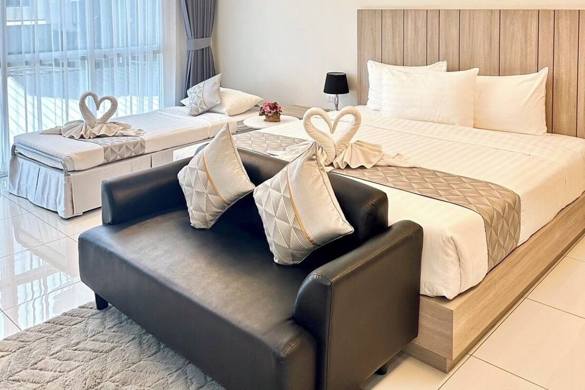 A modern hotel room with a bed, a sofa, and a small table.