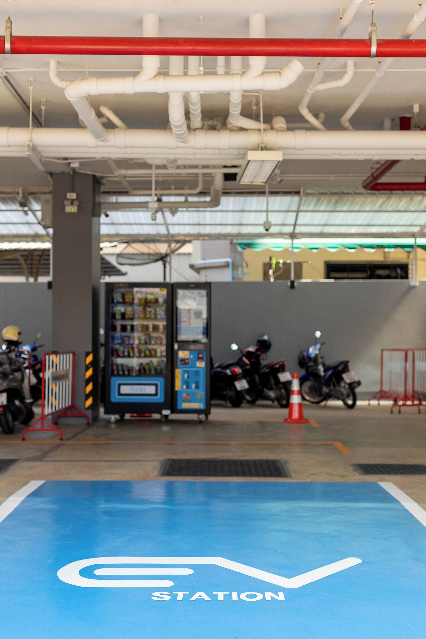 A gas station with a blue floor marked "STATION," a vending machine, and motorcycles parked nearby.