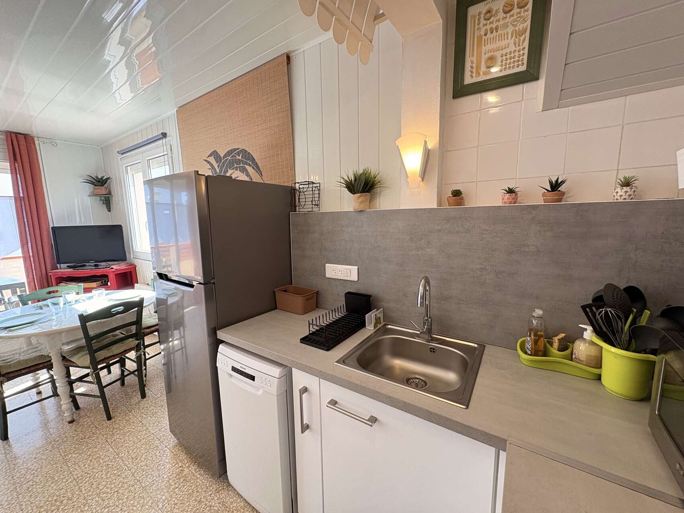 A compact kitchen with a dishwasher, a sink, and a dining area with a table and chairs.