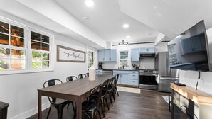 A modern kitchen with a dining area, featuring a wooden table, chairs, and a built-in fireplace.