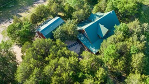 An aerial view of a property with two buildings surrounded by dense forest.