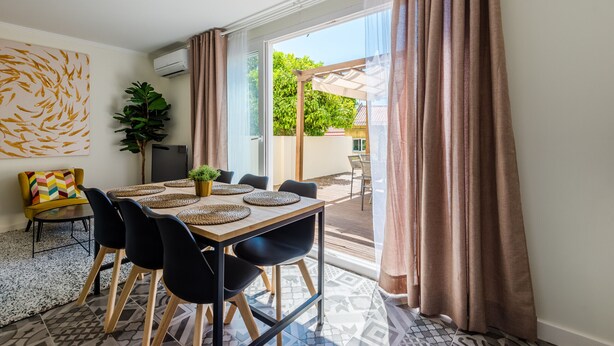 A dining area with a table set for six, black chairs, and a plant on the table.