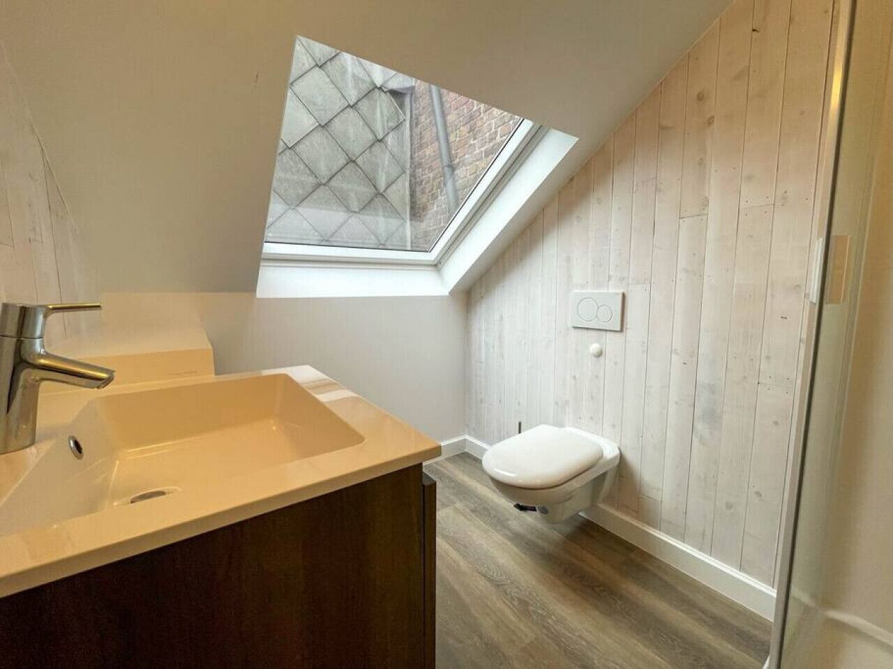 A compact bathroom with a skylight, a sink, and a toilet.