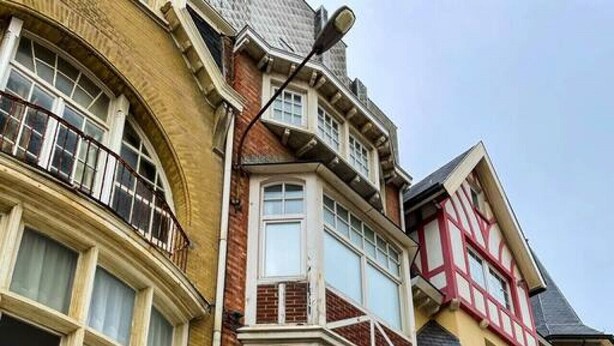 Un edificio a più piani con un abbaino, facciata in mattoni e un mix di stili architettonici tradizionali e moderni.