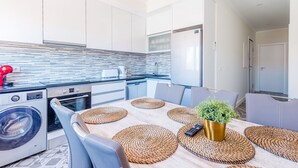 Une cuisine moderne dotée d’un grand îlot central, d’appareils électroménagers intégrés et d’un coin repas avec une table dressée pour quatre personnes.