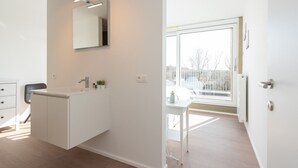 A modern bathroom with a large mirror, a white vanity, and a window providing natural light. - Villa Petit Mousse -Luxurious villa close to beach (Koksijde)