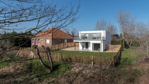 A modern two-story house with a red-roofed brick section and a white section with large windows. - Villa Petit Mousse -Luxurious villa close to beach (Koksijde)