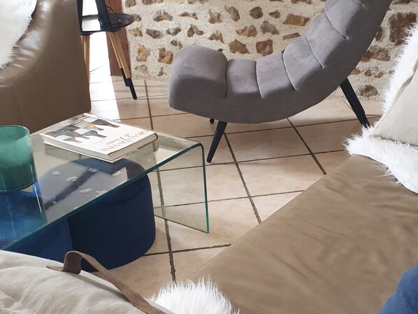 Un saló amb una taula de centre de vidre, un armari gris i un sofà beix.