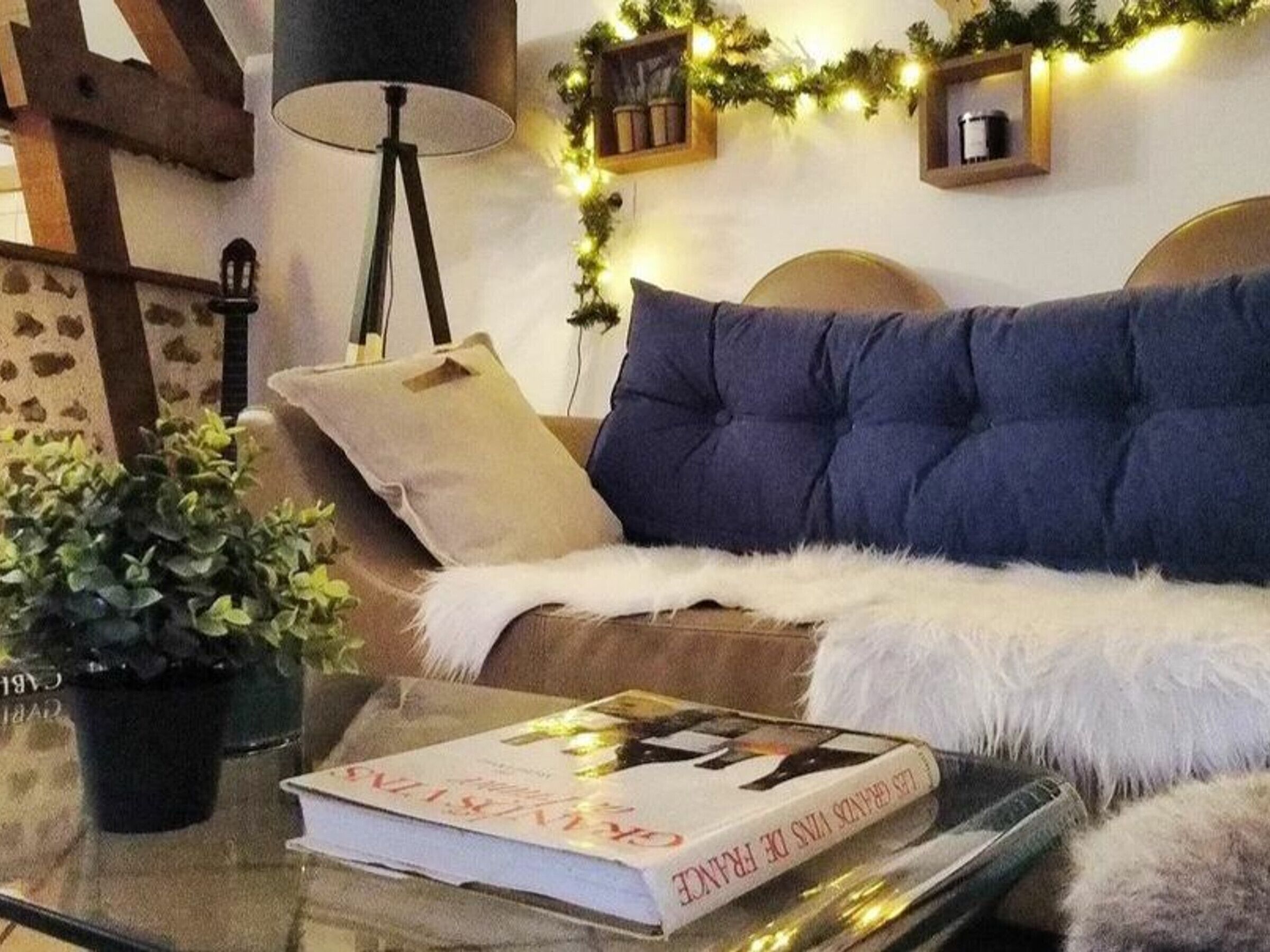 Ein gemütliches Wohnzimmer mit einer Couch, einer Lampe, einem Buch und dekorativer Beleuchtung.