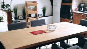 Un comedor con una mesa de madera, sillas grises, un cuenco de cristal y un libro rojo.