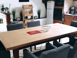 A dining area with a wooden table, grey chairs, a crystal bowl, and a red book. - Charming cottage with nature, Wi-Fi, BBQ and private terrace (Belhomert-Guéhouville)