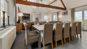 A dining area with wicker chairs and a table, wooden beams on the ceiling, and large windows. - Hoeve t` Korenhof - Koksijde (Koksijde)