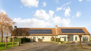 A two-story stone building with a sloped roof, solar panels, and a gravel driveway. - Hoeve t` Korenhof - Koksijde (Koksijde)