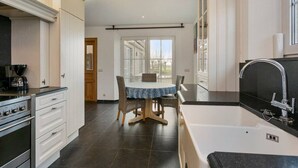 A modern kitchen with a dining area, a large window, and a bathtub. - Hoeve t` Korenhof - Koksijde (Koksijde)
