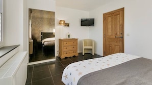 A bedroom with a bed, a wooden wardrobe, a television, and a chair. - Hoeve t` Korenhof - Koksijde (Koksijde)