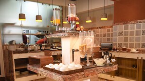 Un bufé de desayuno con diferentes alimentos y una taza de café.