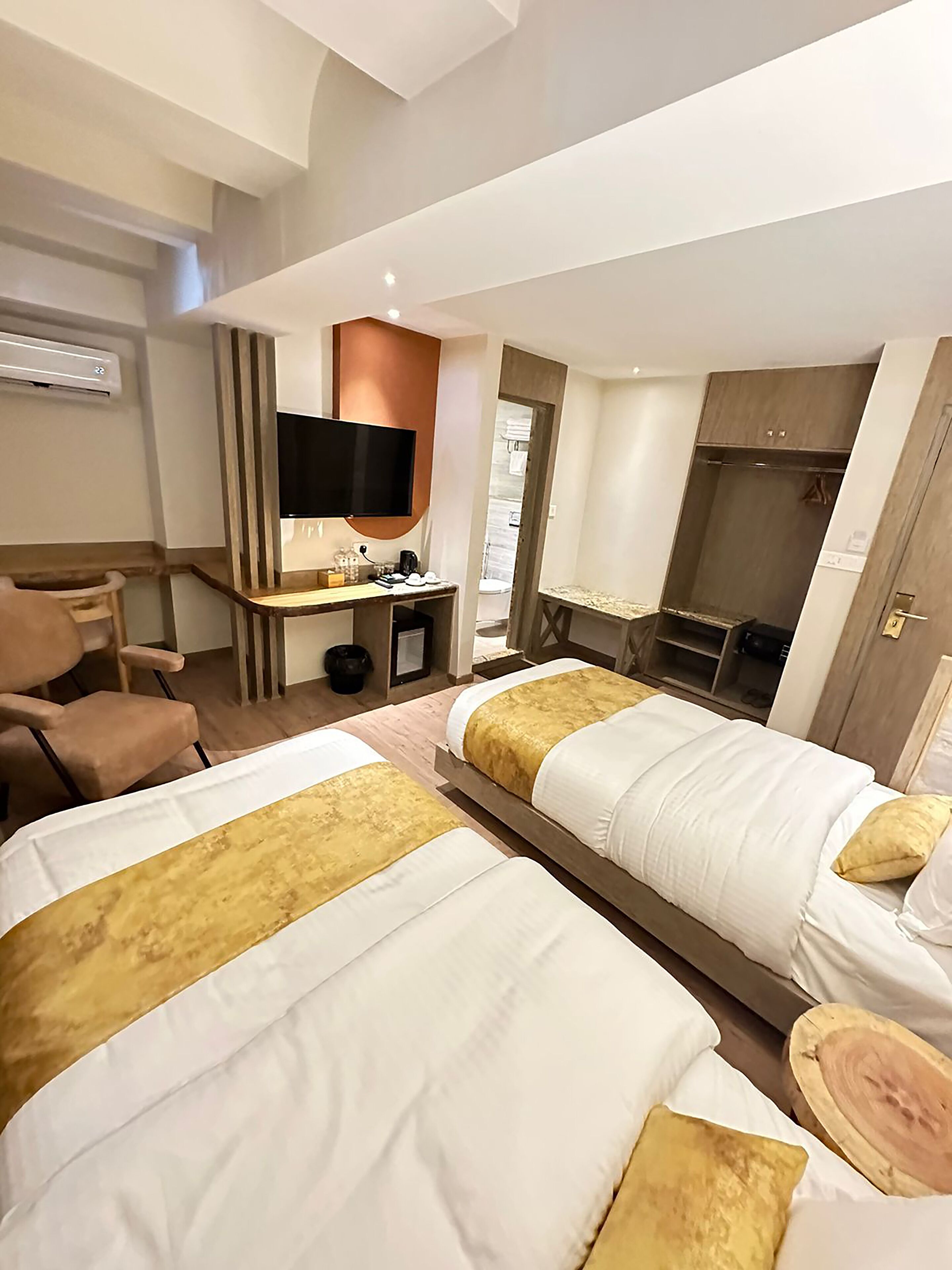 Een hotelkamer met twee bedden, een bureau met een flatscreen televisie, een stoel en een kledingkast.