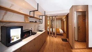 Una habitación de hotel moderna con cocina, piso de madera y una cama con cortinas.