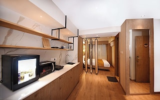 Una habitación de hotel moderna con cocina, piso de madera y una cama con cortinas.