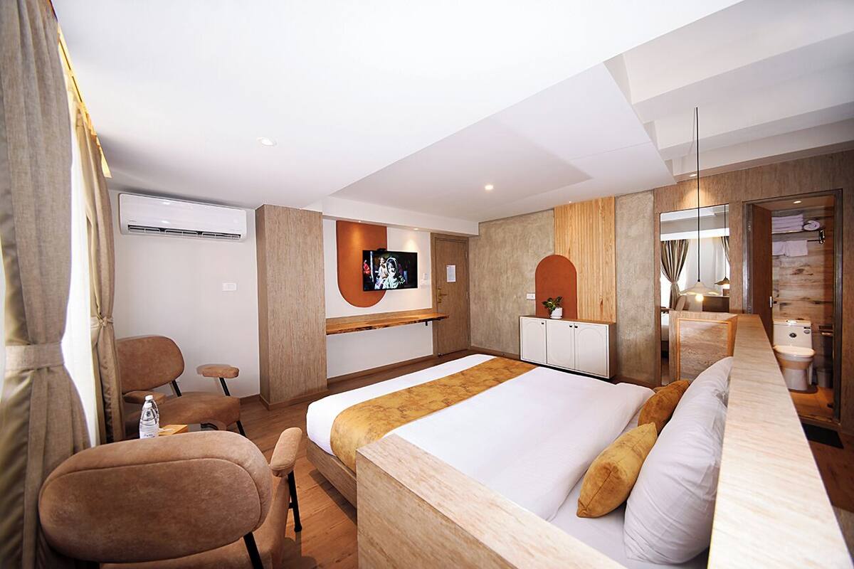 A hotel room with a bed, a TV, a desk, a chair, and a bathroom.