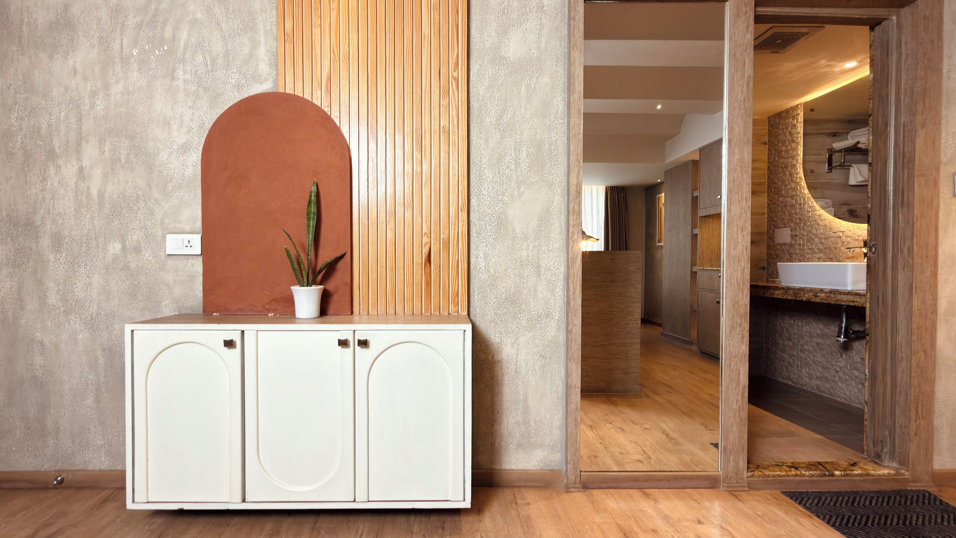 A reception area with a white cabinet, a potted plant, and a wooden panel wall.