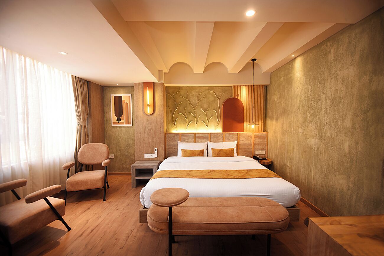 A hotel room with a bed, a chair, a bench, a nightstand, and a wall with a textured design.