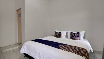 A hotel room with a large bed, white bedding, and decorative pillows with geometric patterns.