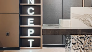 Un interior moderno con un armario, una cama con colcha estampada y letras iluminadas que deletrean "CONCEPT" en el armario.