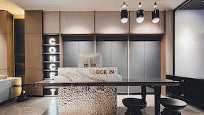 Un mostrador de recepción moderno con un letrero que dice 'CHECK IN', una encimera con diseño de mármol y un letrero que dice 'CONCERN'.