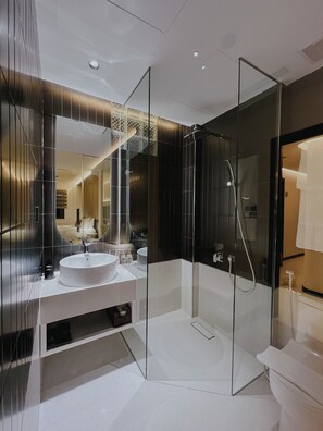 Ein modernes Badezimmer mit einer gläsernen Duschkabine, einem weißen Waschbecken und einem großen Spiegel.