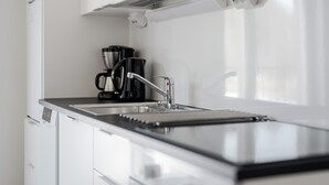 A modern kitchen with a stainless steel sink, a coffee maker, and a built-in oven. - Serviced Apartments Pirkkala by UHANDA  (Pirkkala)