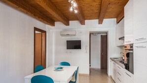 A modern kitchen with white cabinets, a built-in stove, and a flat-screen TV mounted above the counter. - Luna d Argento by Wonderful Italy - Nayra (Syracuse)