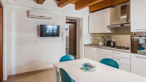 A modern kitchen with white cabinets, a built-in stove, and a flat-screen TV mounted on the wall. - Luna d Argento by Wonderful Italy - Nayra (Syracuse)