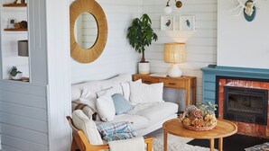 A cozy living room with a white sofa, a round mirror, a fireplace, and a plant. - Wishome—A Fairytale Home to Extend Summer by the Sea (San Vicente de la Barquera)
