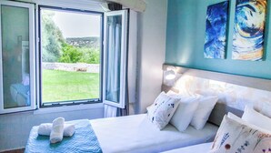 A bedroom with a bed, pillows, a window, and artwork on the wall. - Hem Borta Villa - Next To Platanias, 2min From Beach (Platanias)