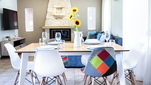 A dining area with a stone fireplace, white chairs, and a table set for four. - Hem Borta Villa - Next To Platanias, 2min From Beach (Platanias)