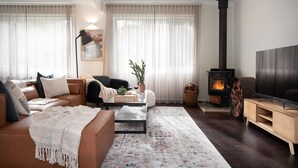 Un salon chaleureux avec un canapé, un fauteuil, une table basse et une cheminée.