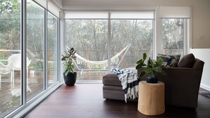 Un salon spacieux doté de grandes fenêtres, d’un hamac et d’un canapé.