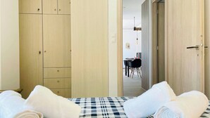 A room with a bed, a wooden wardrobe, and a dining area visible through an open door. - Phaedra House For Relaxing Holidays Near Platanias (Platanias)