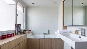 A modern bathroom with a freestanding bathtub, a large mirror, and wooden cabinetry. - Contemporary Heights, by Veeve (Paris)