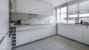 A modern kitchen with white cabinets, a marble backsplash, and a window providing natural light. - Contemporary Heights, by Veeve (Paris)