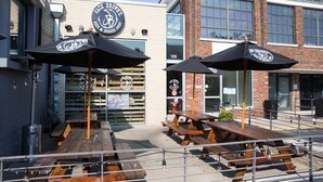 An outdoor seating area with wooden tables and black umbrellas at a restaurant named "Jack Brown's." - Musician's Suite: Luxe Music Row Stay, Walk to Gulch! (Nashville)