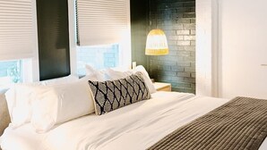 A bedroom with a bed, a nightstand, a ceiling fan, and a window with blinds. - Musician's Suite: Luxe Music Row Stay, Walk to Gulch! (Nashville)