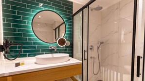 A bathroom with a white sink, a round mirror, and a glass-enclosed shower. - Q Style Hotel  (Trabzon)