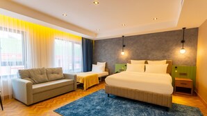 A modern hotel room with a large bed, a sofa, a small table, and a nightstand. - Q Style Hotel  (Trabzon)