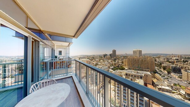 A balcony with a view of a cityscape, including high-rise buildings and a clear sky. - Savyon V.I.E.W - Luxury 3BR w/ Har HaBayit View (Jerusalem)