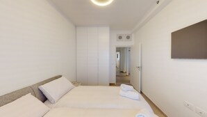 A hotel room with a bed, a wardrobe, a mirror, and a door leading to another room. - Savyon V.I.E.W - Luxury 3BR w/ Har HaBayit View (Jerusalem)