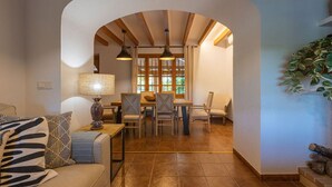 Una sala de estar acogedora con un sofá, una mesa de comedor con sillas y un amplio ventanal con cortinas.